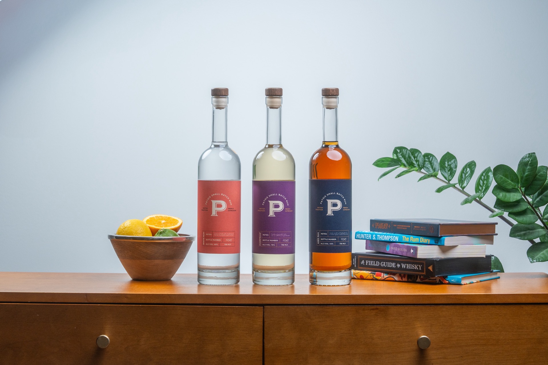 The Patois small-batch rum range — white, overproof, and aged — on a midcentury credenza