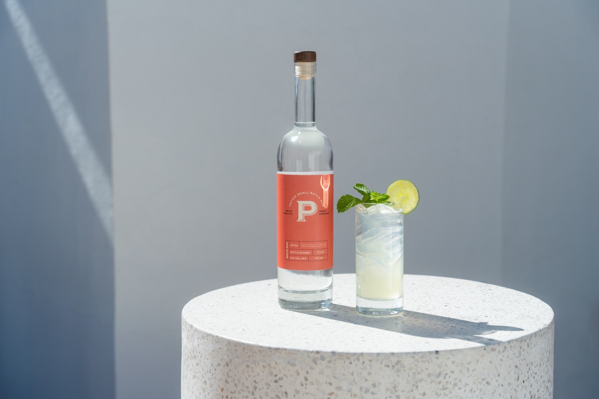 Patois white rum with a mint-and-lime highball on a terrazzo plinth