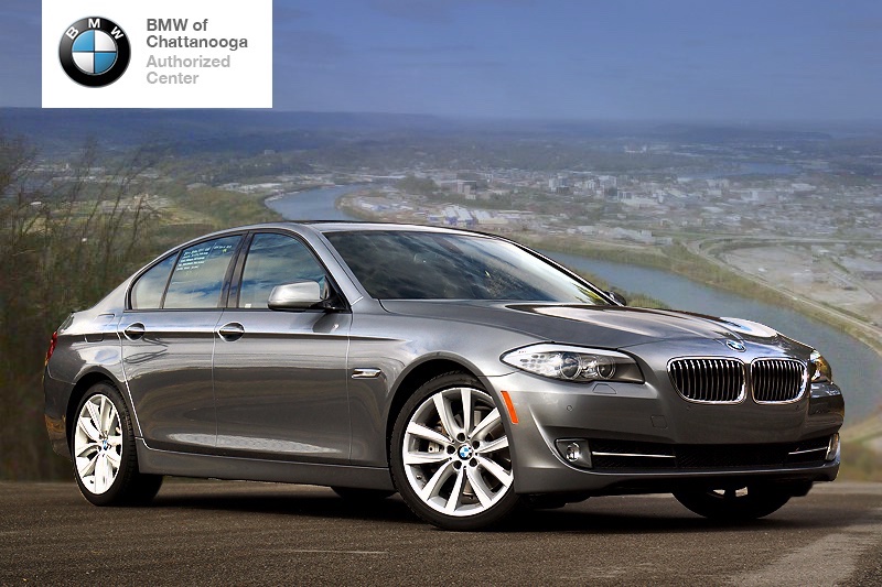 Composited dealer ad — a BMW 5-series cut onto a Chattanooga river-bend overlook