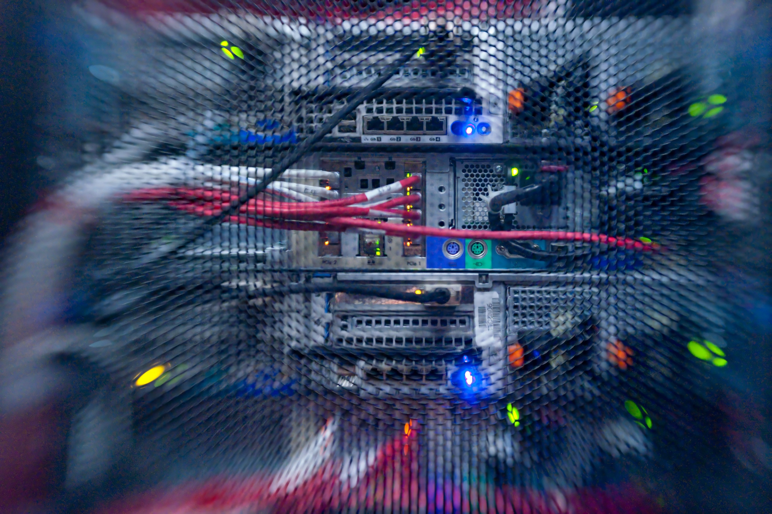 Server rack detail through mesh — colorful cabling and LEDs in soft focus