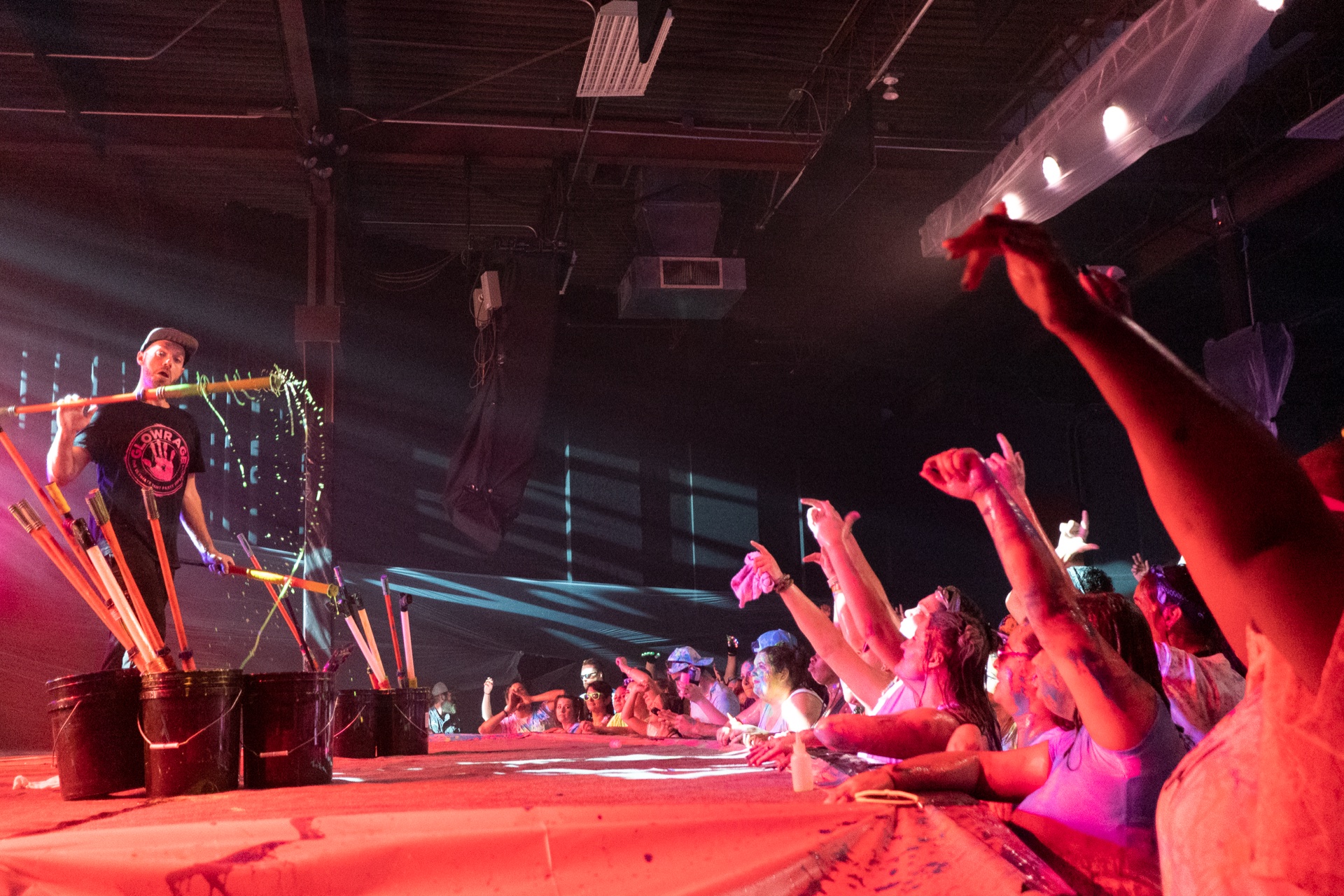 A performer whips neon paint off a mop handle toward the front row